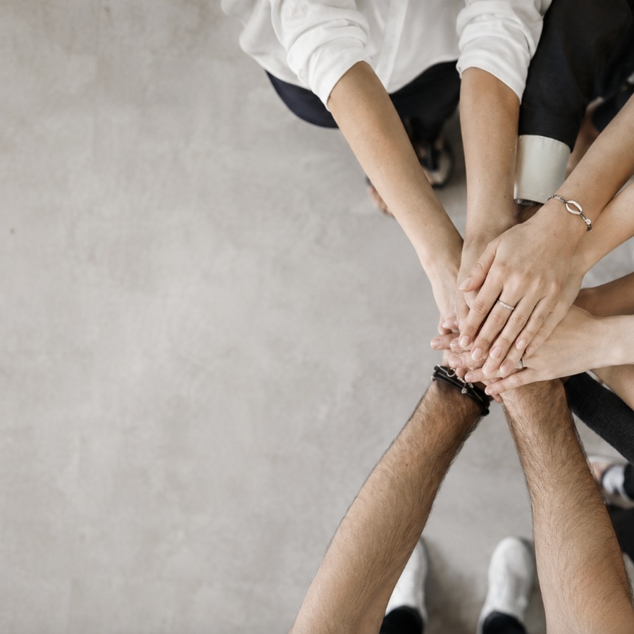 Team members stacking hands together | McSwain Carpets & Floors